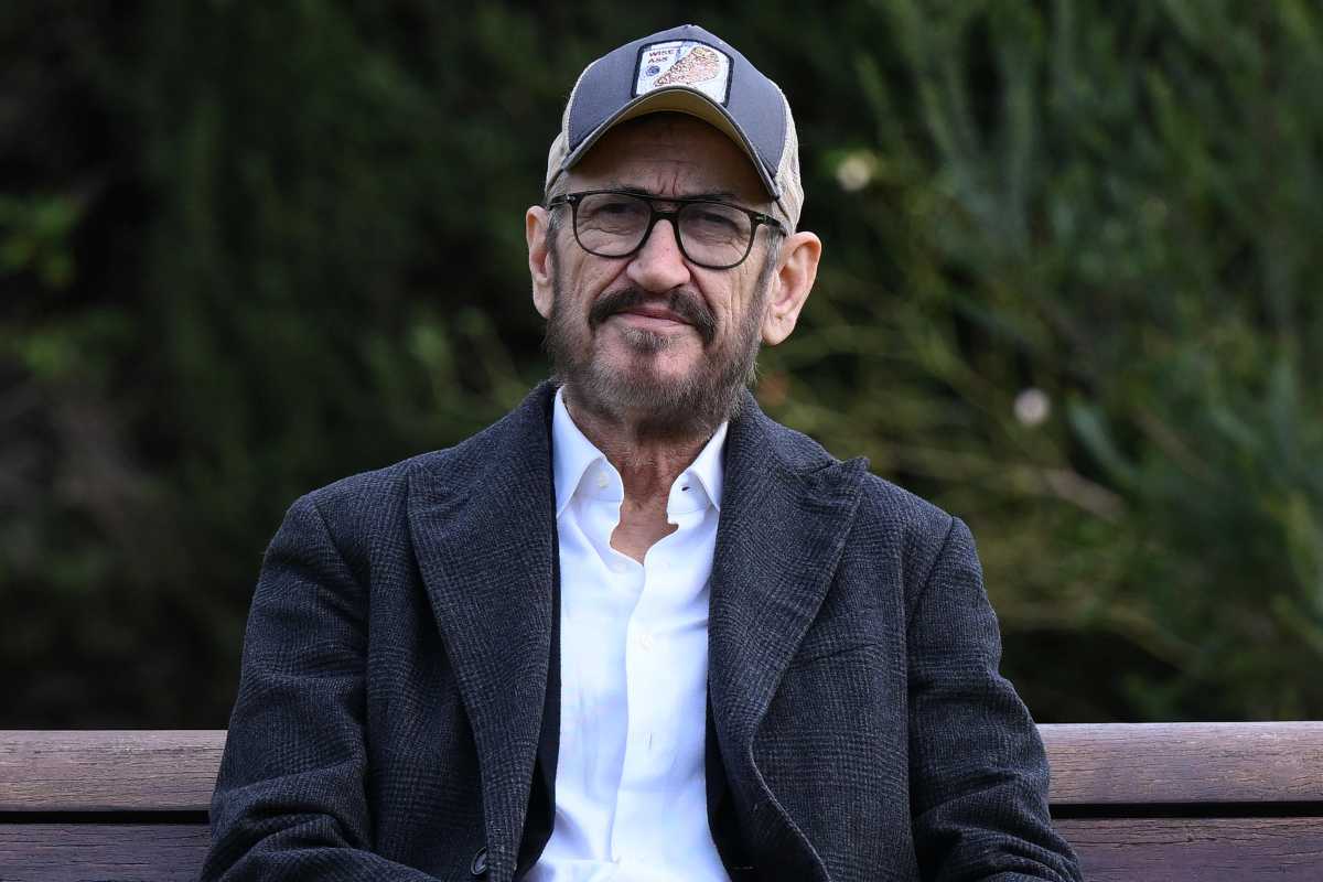 Marco Giallini con il berretto seduto su una panchina