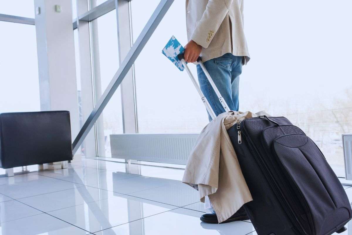 Viaggiatore che cammina in aeroporto con trolley