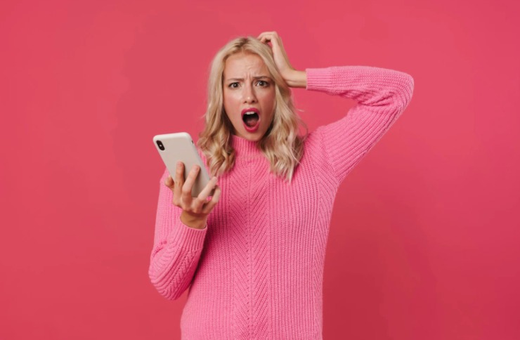 donna con espressione sconvolta e la bocca aperta con il cellulare in mano