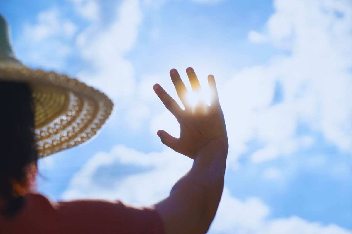 persona copre il sole con una mano