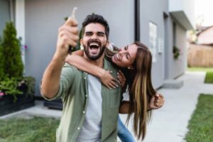 uomo che esulta con in mano una chiave e dietro di lui una donna che lo abbraccia