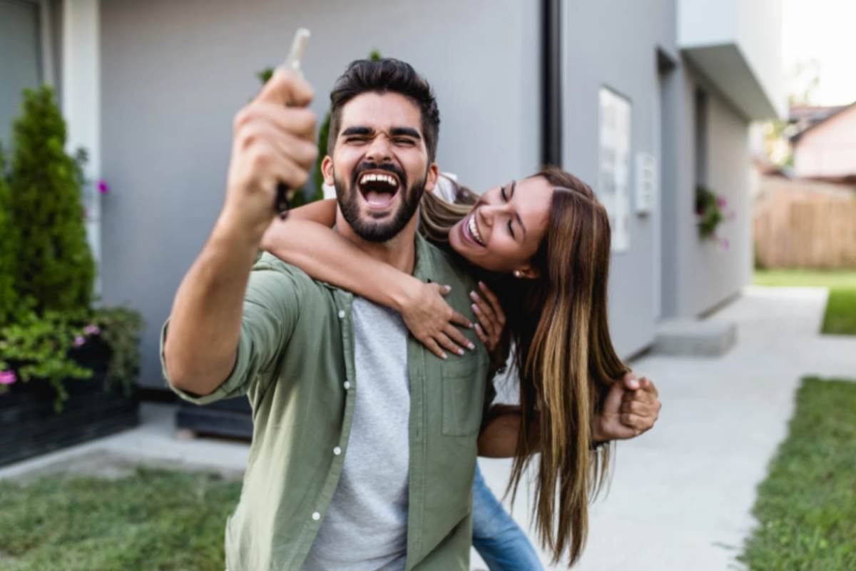 uomo che esulta con in mano una chiave e dietro di lui una donna che lo abbraccia