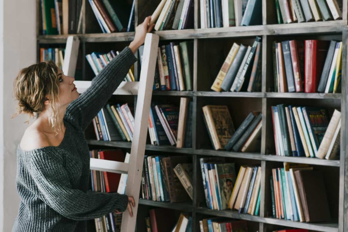 Donna con una sala davanti a una libreria piena di scaffali