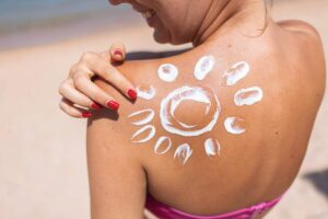 Donna con un sole disegnato con la crema solare sulla schiena