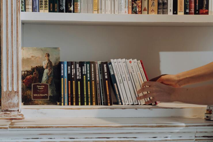 Persona sistema i libri su uno scaffale